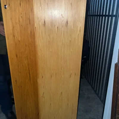 Sale Photo Thumbnail #69: Tall oak storage cabinet with a single door, featuring a natural wood grain finish and a simple silver pull handle.