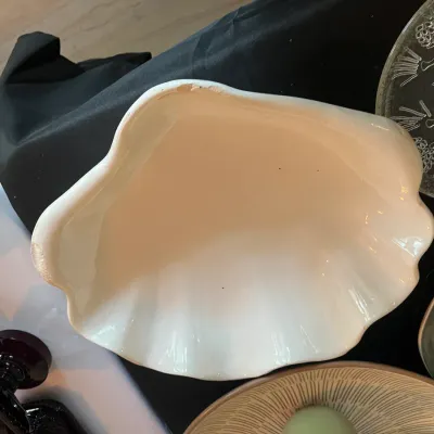 Vintage white ceramic clam shell bowl, showing some minor wear and chipping along the rim.