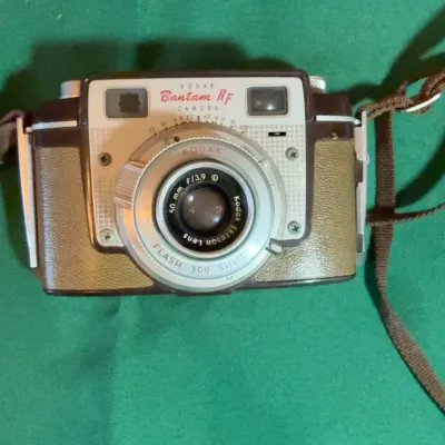 Vintage Kodak Bantam RF camera with a 50mm f/3.9 Kodak Ektanon lens, featuring a brown and tan body with a carrying strap, circa 1953-1957.
