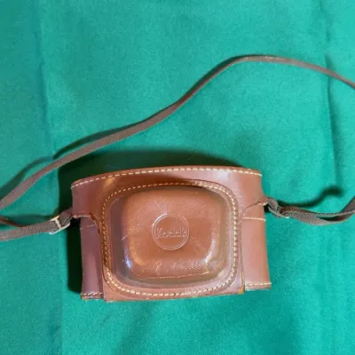Vintage brown leather Kodak camera case with an adjustable shoulder strap, featuring an embossed Kodak logo on the front.