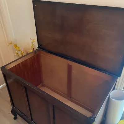 Vintage dark wood blanket chest with a hinged lid, paneled front, and cabriole feet, showing some surface wear.