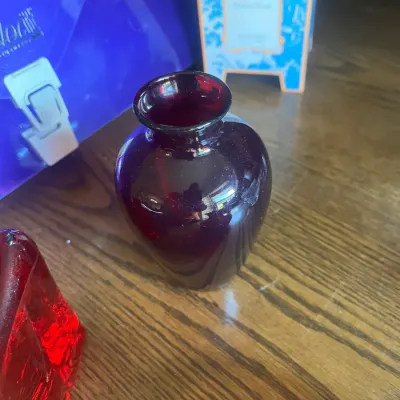 Small vintage ruby red glass vase with a flared rim, displayed on a wooden surface.