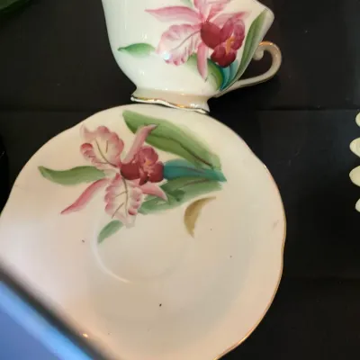 Vintage porcelain teacup and saucer set featuring a hand-painted pink orchid design with gold trim.