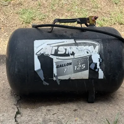 AirStream 7-gallon, 125 PSI portable air tank showing significant wear and peeling on the label.