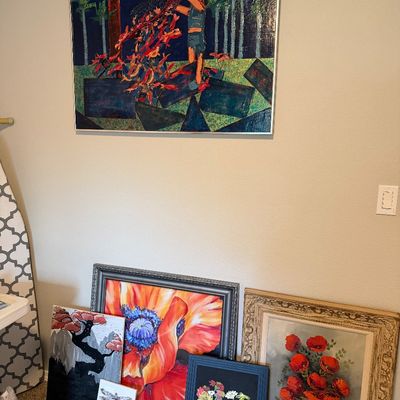 Sale Photo Thumbnail #28: Collection of framed wall art, including a large abstract painting on the wall and several floral and nature-themed paintings leaning on the floor.