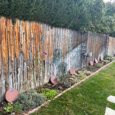 Sale Photo Thumbnail #38: Assorted garden decor and accessories, including metal trellises, tomato cages, and round red stepping stones, arranged along a wooden fence line.
