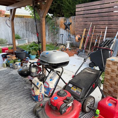 Sale Photo Thumbnail #42: Troy-Bilt walk-behind lawn mower, portable charcoal grills, bags of Kingsford charcoal, and various garden tools arranged on a patio.
