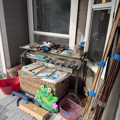 Sale Photo Thumbnail #40: Assorted gardening tools, a woven storage chest, bamboo stakes, and outdoor decor items displayed on a patio.