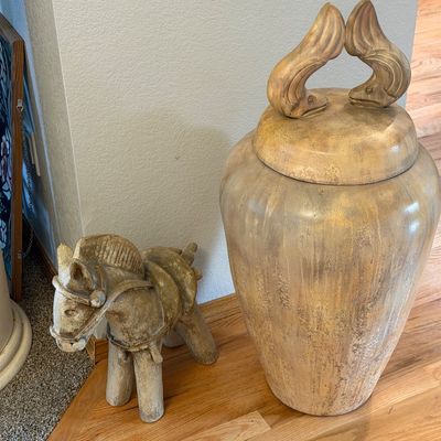 Sale Photo Thumbnail #9: Large decorative ceramic urn with a fish-motif lid handle, paired with a rustic ceramic horse figurine, both featuring a distressed beige and gold finish.