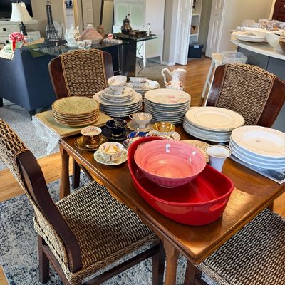 Sale Photo Thumbnail #12: Wooden dining table and woven-back chairs displaying various sets of vintage porcelain dinnerware, teacups, and colorful serving bowls.