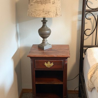 Sale Photo Thumbnail #30: Traditional mahogany-finish nightstand featuring a single drawer with a brass pull, open shelving, and cabriole legs, topped with a contemporary urn-style table lamp.