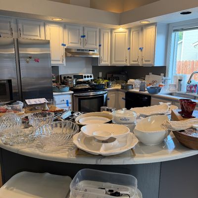 Sale Photo Thumbnail #24: Assorted kitchenware and serving dishes, including CorningWare, cut glass bowls, and ceramic platters, displayed on a kitchen island.