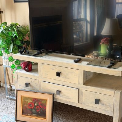 Sale Photo Thumbnail #19: Distressed white-washed wooden media console with four drawers and black hardware, shown holding a flat-screen television.