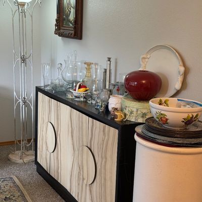 Sale Photo Thumbnail #2: Mid-century modern style credenza with faux-wood grain doors and circular handles, displaying various glassware, ceramics, and decorative items.