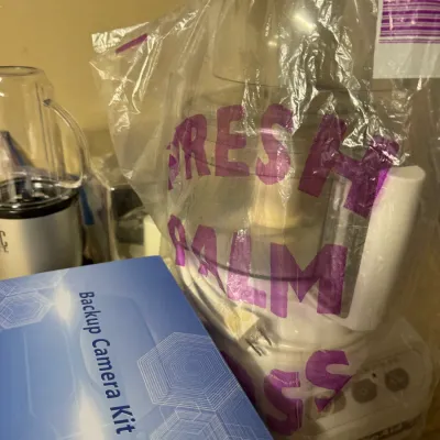 KitchenAid food processor wrapped in a plastic bag, displayed next to a boxed backup camera kit.