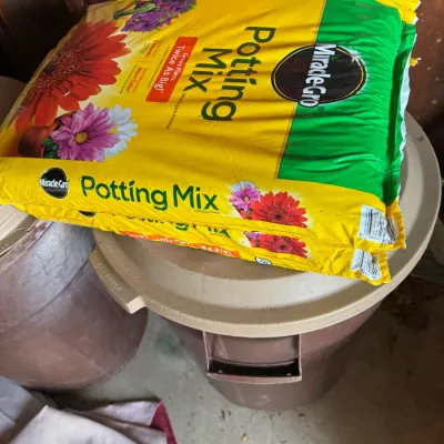 Two bags of Miracle-Gro Potting Mix stacked on top of a brown plastic storage bin.