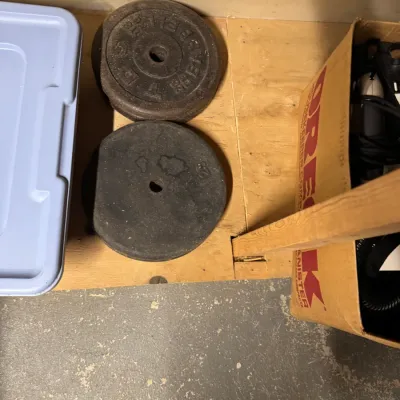 Two vintage cast iron barbell weight plates, including a York Barbell 25-pound plate showing some surface rust and wear.