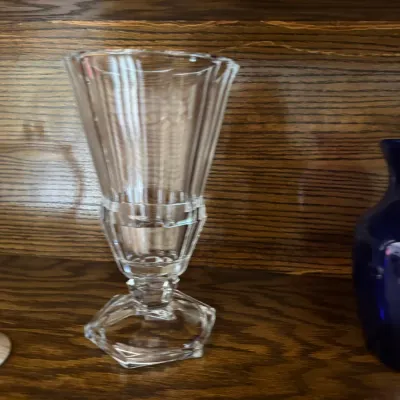 Sale Photo Thumbnail #195: Vintage clear cut glass footed vase with a ribbed body and hexagonal base, displayed on a wooden shelf.