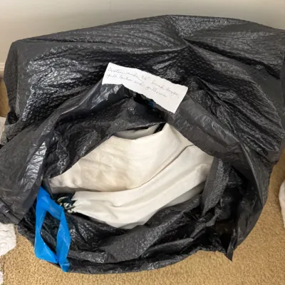 Custom-made 84-inch lined drapes, gold backs, and pillows, stored inside a black plastic bag with a handwritten descriptive note.