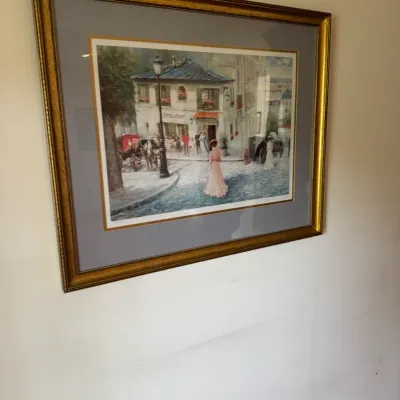 Sale Photo Thumbnail #126: Framed impressionist-style print depicting a bustling European street scene with figures and a horse-drawn carriage, housed in a gold-finished frame with double matting.
