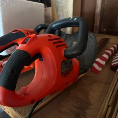 Black & Decker electric hedge trimmer with orange housing and black handles, showing some signs of use.