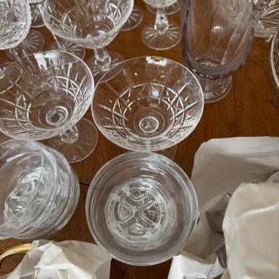 Sale Photo Thumbnail #108: Collection of vintage cut crystal glassware, including champagne coupes and dessert dishes, displayed on a wooden surface.