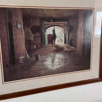 Sale Photo Thumbnail #151: Framed and matted print depicting a rustic stable scene with horses and dogs, housed in a dark wood frame.