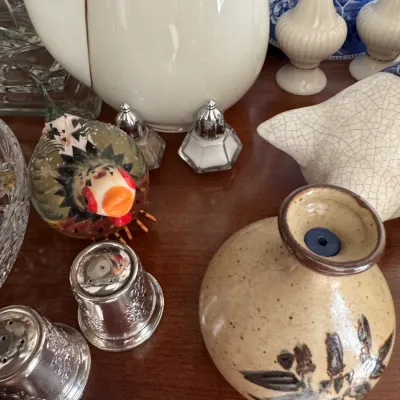 Sale Photo Thumbnail #140: Assorted vintage tabletop items including a hand-painted ceramic bird figurine, miniature glass salt and pepper shakers, silver-plated shakers, and a speckled stoneware vase.