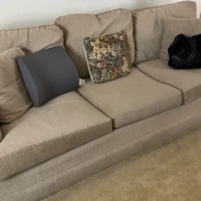 Sale Photo Thumbnail #150: Three-cushion sofa upholstered in a beige corduroy fabric, shown with various accent pillows.