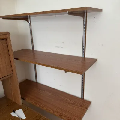 Three-tier wall-mounted shelving unit with wood-grain laminate shelves and metal standards.