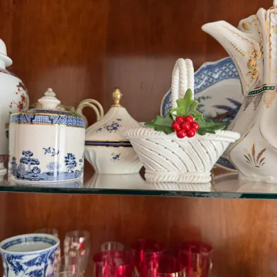 Sale Photo Thumbnail #134: Assorted vintage porcelain and glassware, including a Blue Willow lidded jar, a white woven basket with holly detail, and red-tinted goblets.