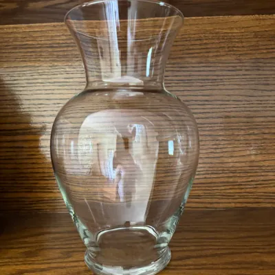 Sale Photo Thumbnail #167: Classic clear glass urn-shaped flower vase, displayed on a wooden shelf.