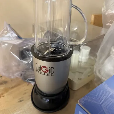 Magic Bullet personal blender with a silver and black motor base and a clear plastic blending cup with a handle.