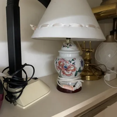 Vintage ginger jar style table lamp featuring a hand-painted floral design, paired with a white shade accented by a woven ribbon.