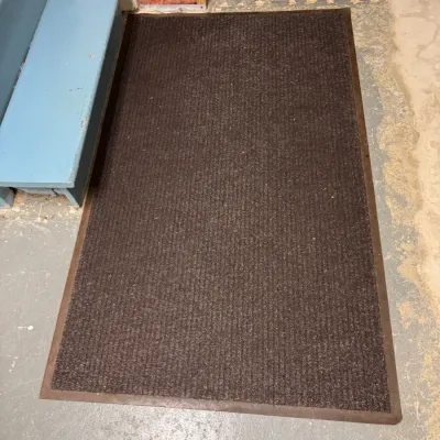 Large brown ribbed utility doormat with a rubber border, showing light wear.