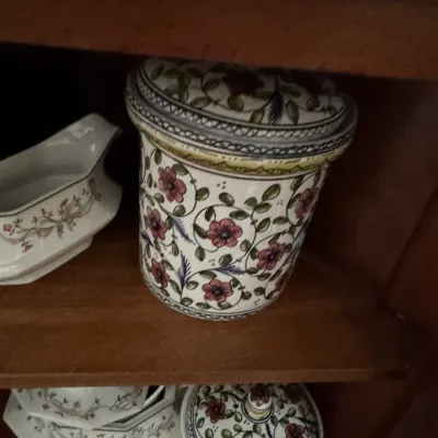 Sale Photo Thumbnail #121: Vintage hand-painted ceramic canisters featuring a floral vine motif in red, green, and blue, displayed on wooden shelves.