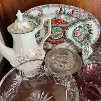 Sale Photo Thumbnail #130: Assortment of vintage glassware and porcelain, including a Rose Medallion style platter, a floral teapot, a cut crystal bowl, and a purple glass vase.