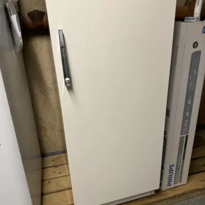 Vintage white upright freezer with a textured black handle, resting on a wooden pallet.
