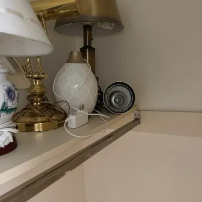 Assorted table lamps, including a brass pharmacy-style lamp, a white ceramic lamp with floral details, and a modern white textured lamp...