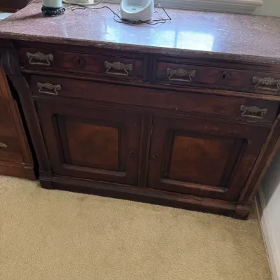 Antique Eastlake-style walnut commode featuring a pink marble top, two upper drawers, one wide middle drawer, and a double-door lower...