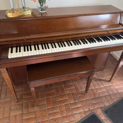 Sale Photo Thumbnail #185: Vintage Baldwin spinet piano in a warm wood finish, complete with a matching bench.