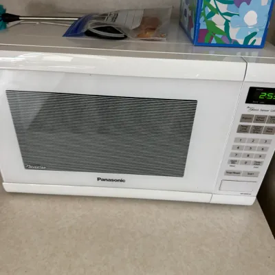 Sale Photo Thumbnail #116: Panasonic Genius Sensor 1200W white countertop microwave oven, showing light wear from use.