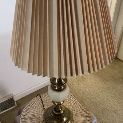 Sale Photo Thumbnail #152: Vintage brass table lamp featuring a white glass accent on the column and a tall, pleated beige fabric lampshade.