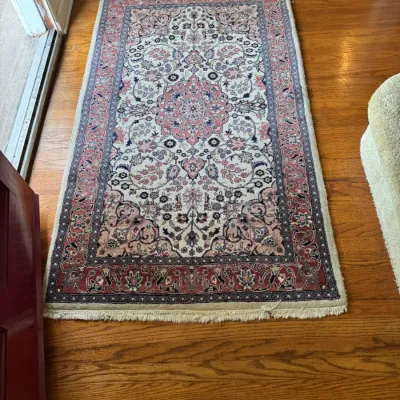 Traditional Persian-style area rug featuring an intricate floral medallion design in shades of pink, cream, and navy blue with fringed ends.
