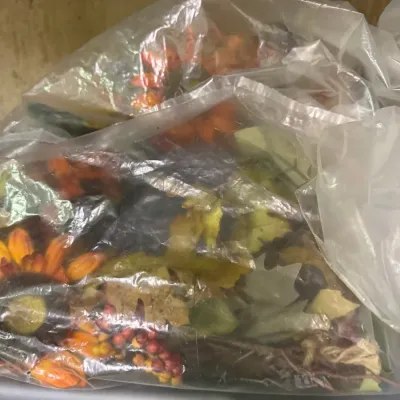 Assorted autumn-themed faux floral arrangements and foliage, stored in clear plastic bags.