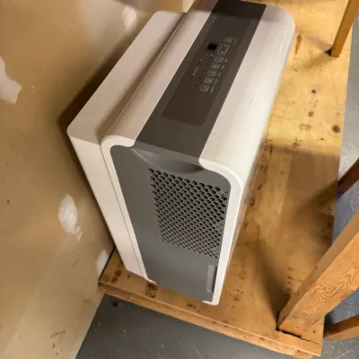 LG portable dehumidifier in white and grey, featuring a digital control panel on top and a honeycomb-patterned air intake grille on the...