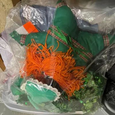Vintage handmade St. Patrick's Day themed rag doll with orange yarn hair and a green outfit, packaged in a clear plastic bag.