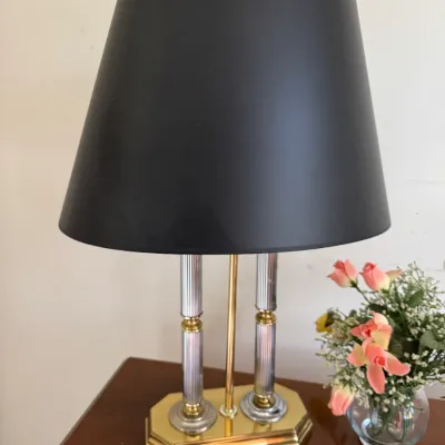Vintage table lamp featuring a brass and chrome double-column base, topped with a black tapered drum shade.