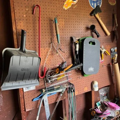 Sale Photo Thumbnail #198: Assorted vintage and modern hand tools, garden implements, and workshop accessories hanging on a pegboard organizer.