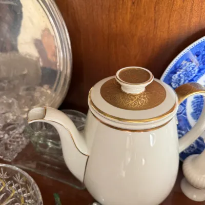 Sale Photo Thumbnail #141: Vintage white porcelain teapot with elegant gold filigree detailing on the lid and gold trim, displayed alongside other glassware and tableware.